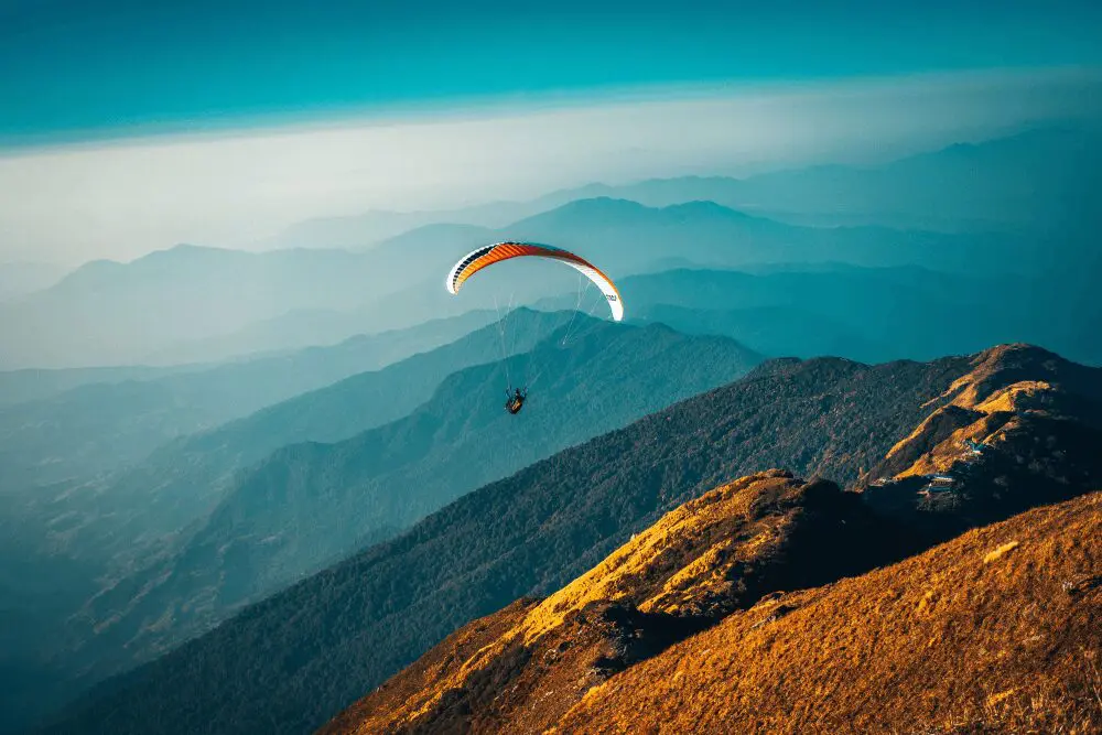 A person is flying a parachute over the mountains.